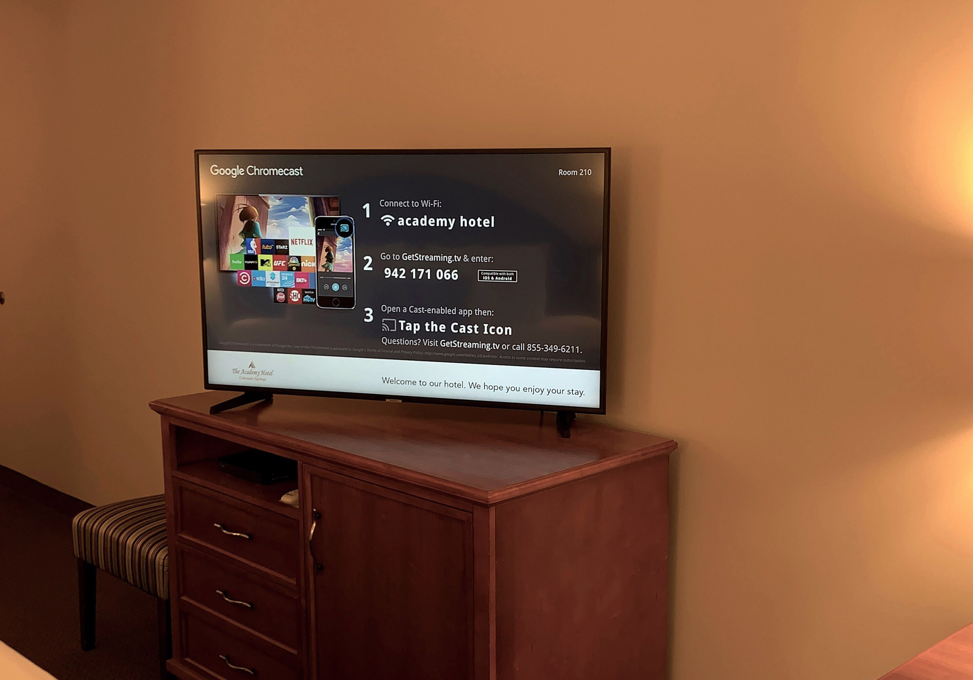 A television displaying Google Chromecast instructions for connecting to Wi-Fi, with a hotel name and contact number visible.