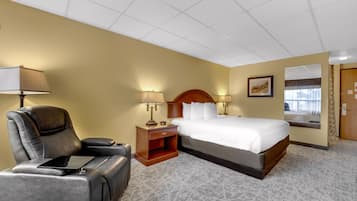 Une chambre d’hôtel avec un lit, une chaise, une table de chevet et une lampe.