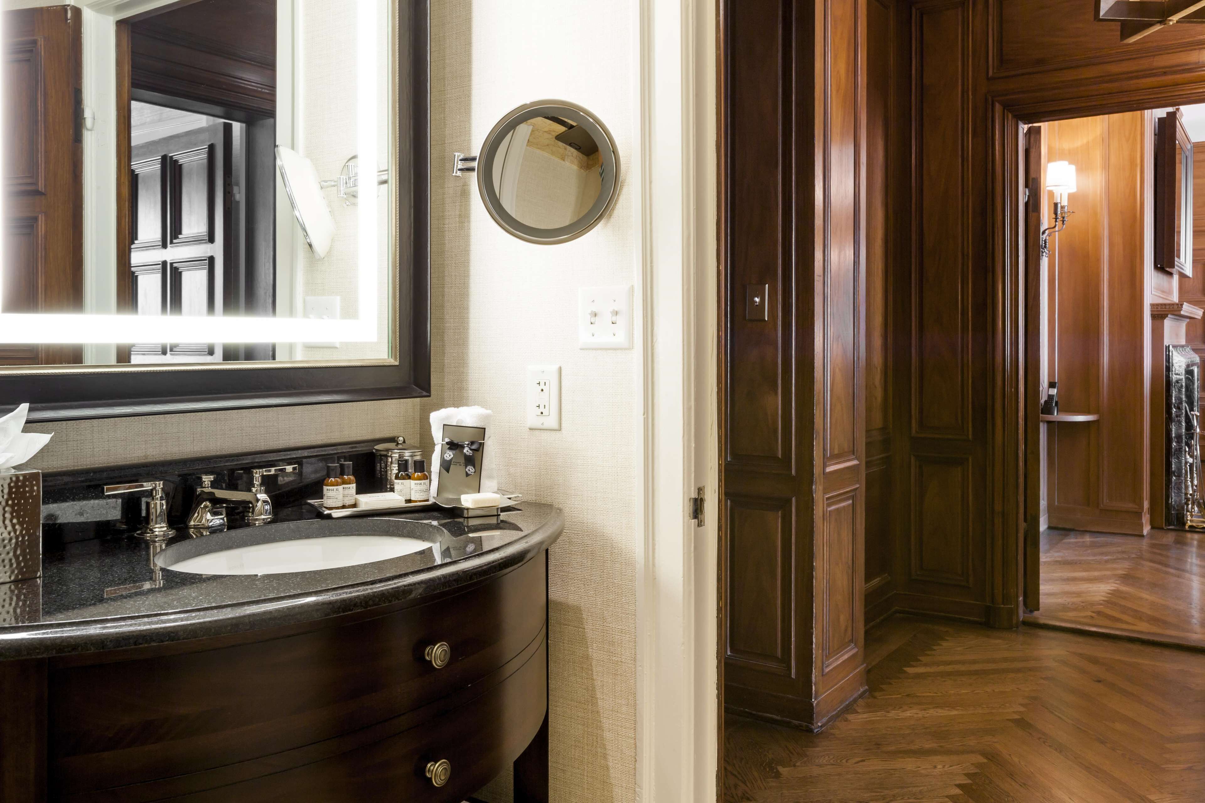 A bathroom with a dark wood vanity, a large mirror, and a round mirror above the sink.