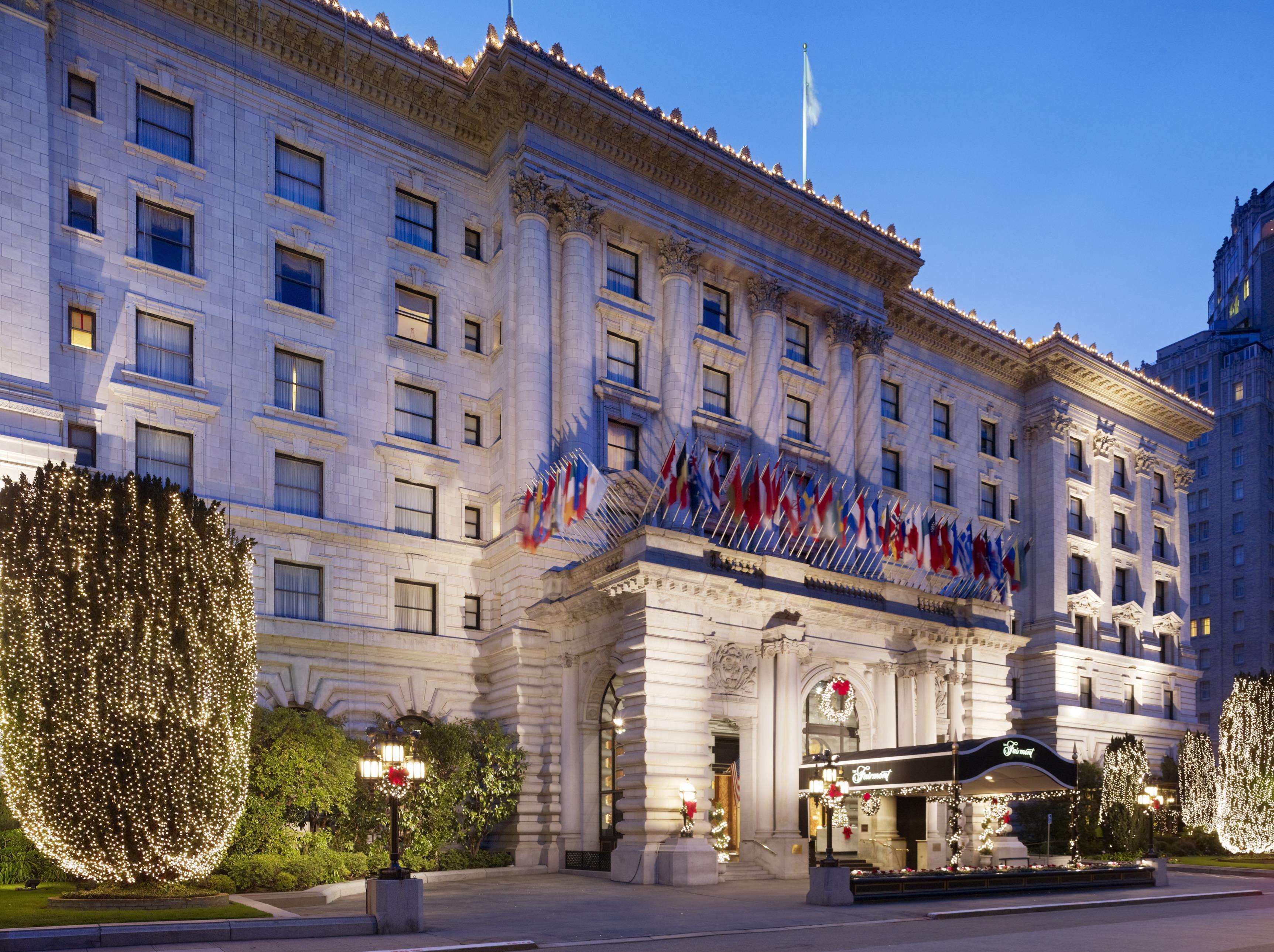 A large, historic building with multiple flags, a grand entrance, and a well-lit facade.