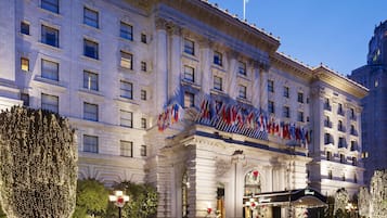 A large, historic building with multiple flags, a grand entrance, and a well-lit facade.