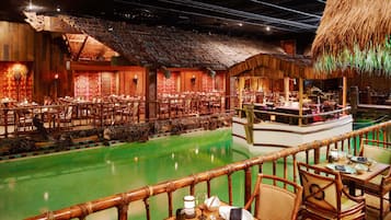 En restaurant med pool, træborde og stole.