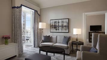 Una habitación de hotel con sofá, mesa de centro, televisión y lámpara.