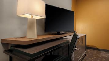 Une chambre d’hôtel équipée d’un bureau, d’une télévision à écran plat, d’une lampe et d’une chaise.