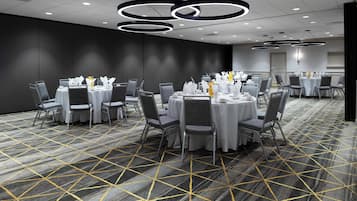 A conference room with round tables, grey chairs, and a patterned carpet.