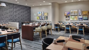 A modern restaurant with booths and tables, geometric patterned walls, and framed artwork. - Holiday Inn Boston - Dedham Hotel & Conference Center by IHG (Dedham)