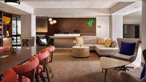 A modern hotel lobby with a reception desk, seating area, and a patterned carpet. - Holiday Inn Boston - Dedham Hotel & Conference Center by IHG (Dedham)