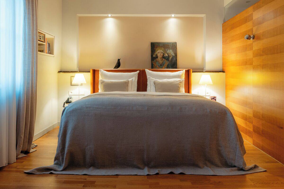 Una habitación de hotel con una cama grande, dos lámparas de noche, un cuadro en la pared y un revestimiento de pared de madera.