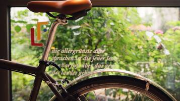 A bicycle with a brown seat and a rear view of a window with greenery outside.