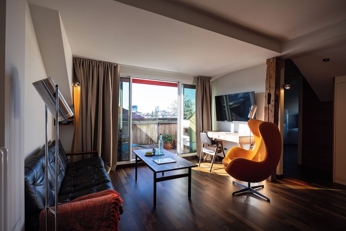 Una sala de estar moderna con sofá, una mesa, televisión y una silla.