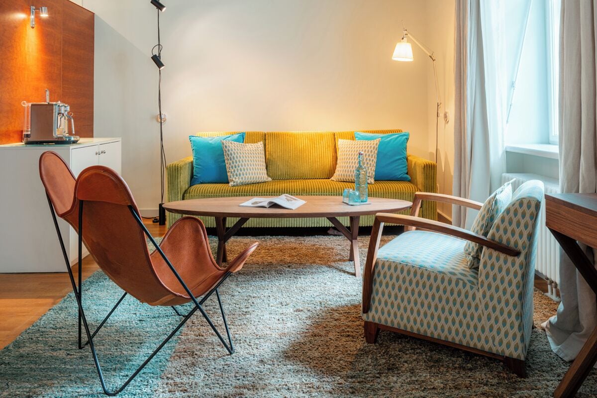 A modern living room with a sofa, two armchairs, a coffee table, and a small side table.