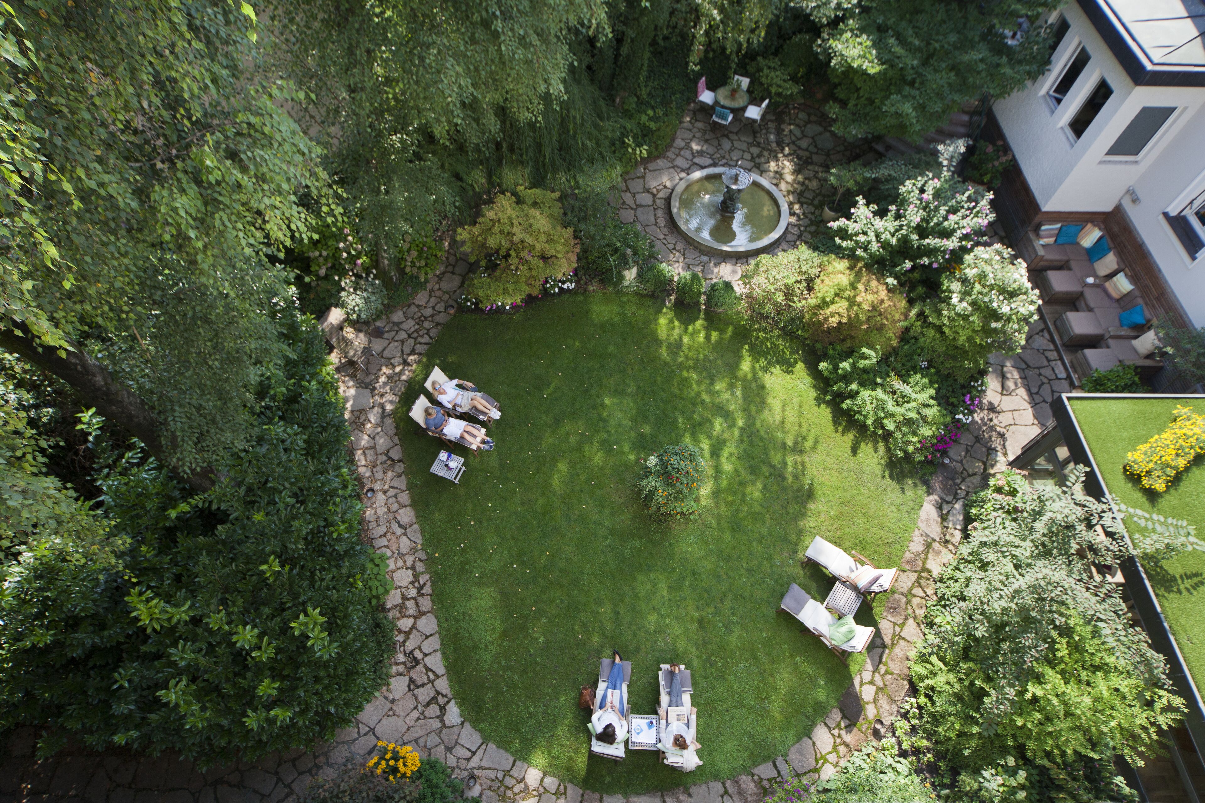 An aerial view of a well-maintained garden with a circular lawn, stone pathways, and outdoor seating areas.