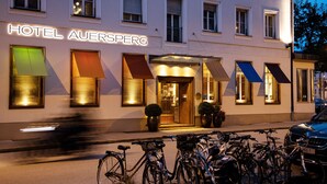 A hotel named HOTEL AUESPERG with a modern facade, large windows, and a bicycle parking area in front.