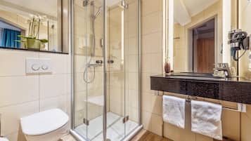Ein modernes Badezimmer mit einer Duschkabine, einer Toilette, einem Waschbecken mit schwarzer Arbeitsplatte und einem Spiegel.