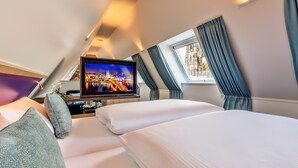 Una habitación de hotel con dos camas, televisión y una ventana con cortinas.