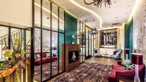 Una sala de estar moderna con un televisor grande, asientos cómodos, un tapete estampado y un jarrón decorativo con flores.