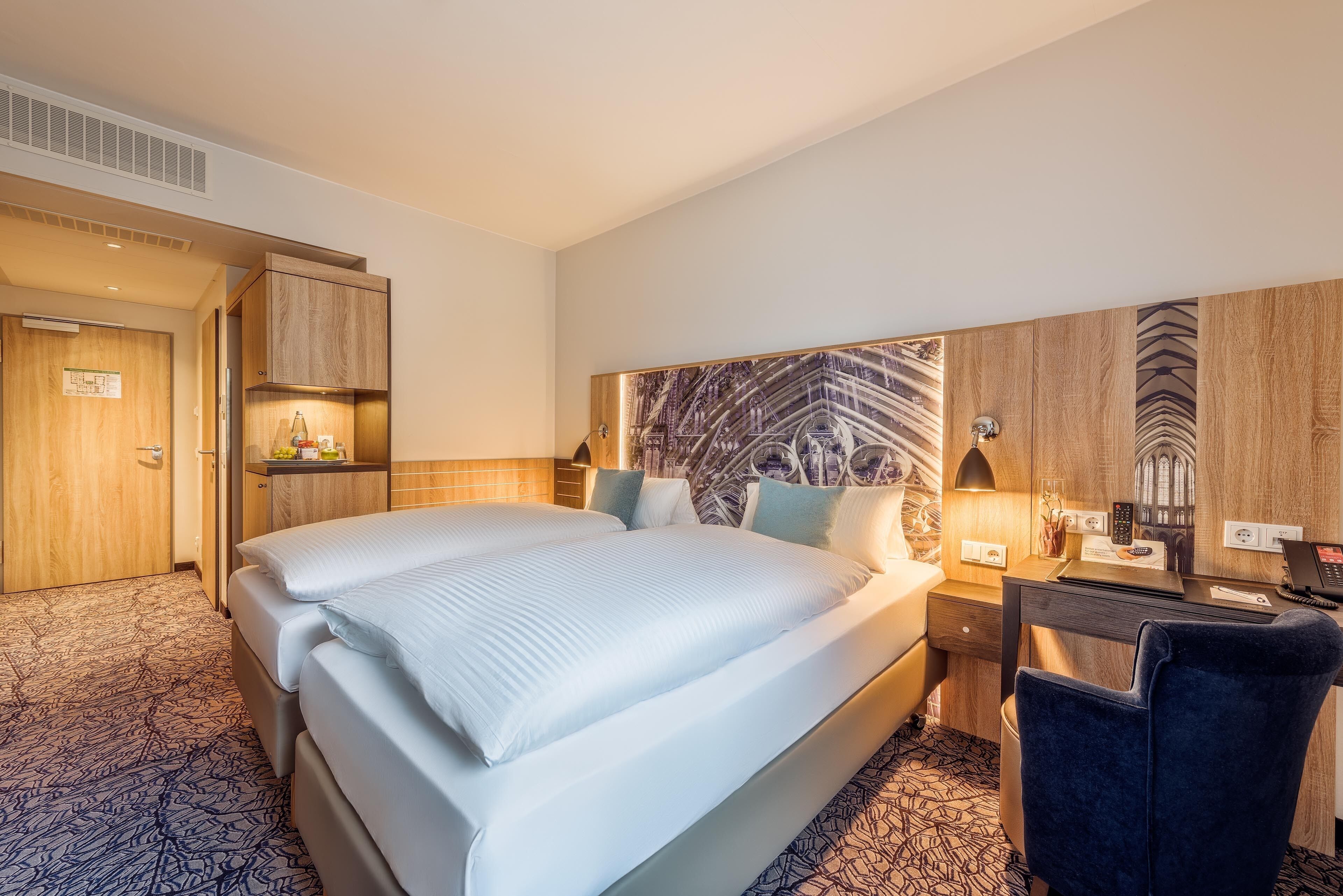 Habitación de hotel con una cama grande, un escritorio con computadora y una pequeña zona de estar.