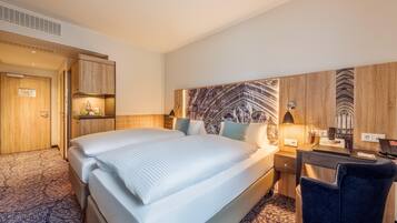 Habitación de hotel con una cama grande, un escritorio con computadora y una pequeña zona de estar.
