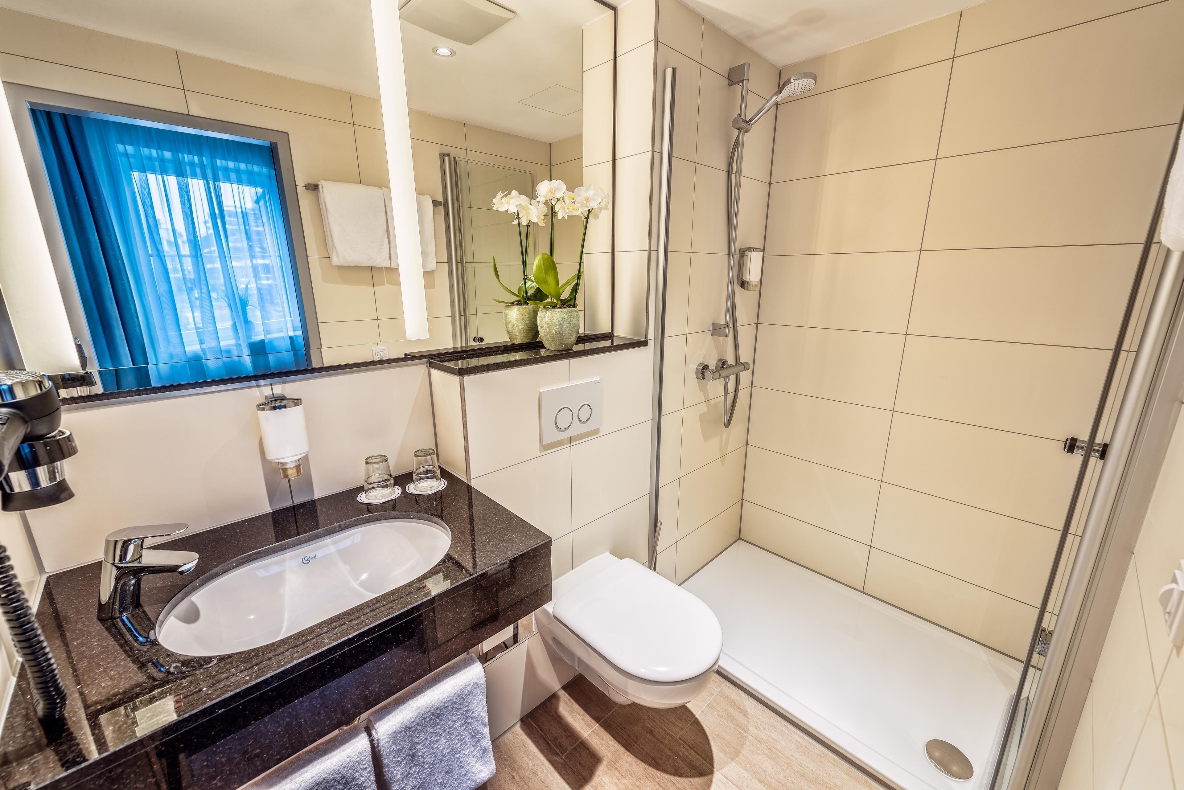 A modern bathroom with a sink, toilet, and glass-enclosed shower.
