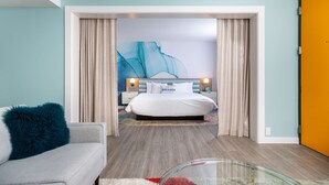 A modern bedroom with a bed, a glass coffee table, and a view into another room.