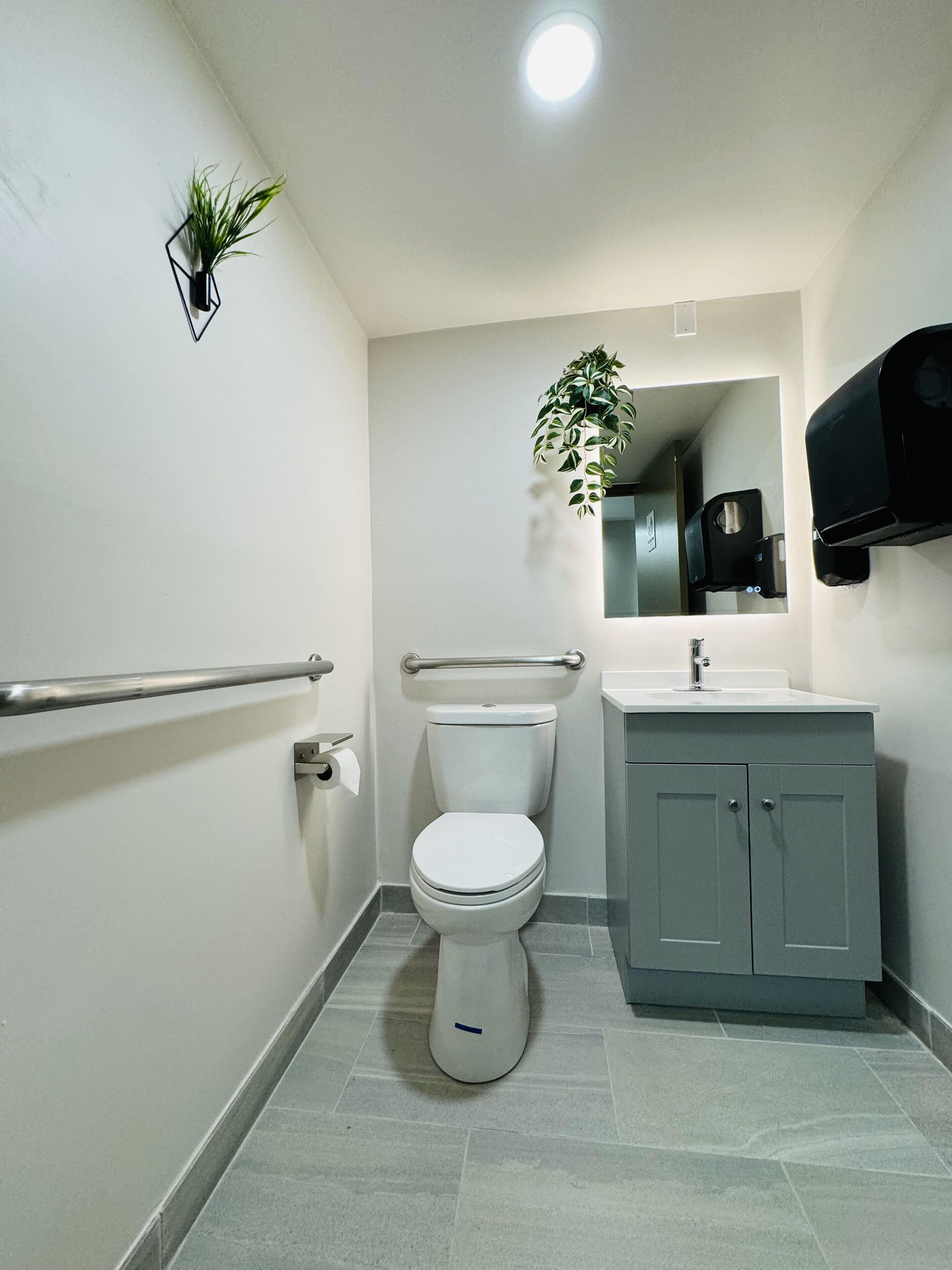 A modern bathroom with a toilet, sink, and a hand dryer.