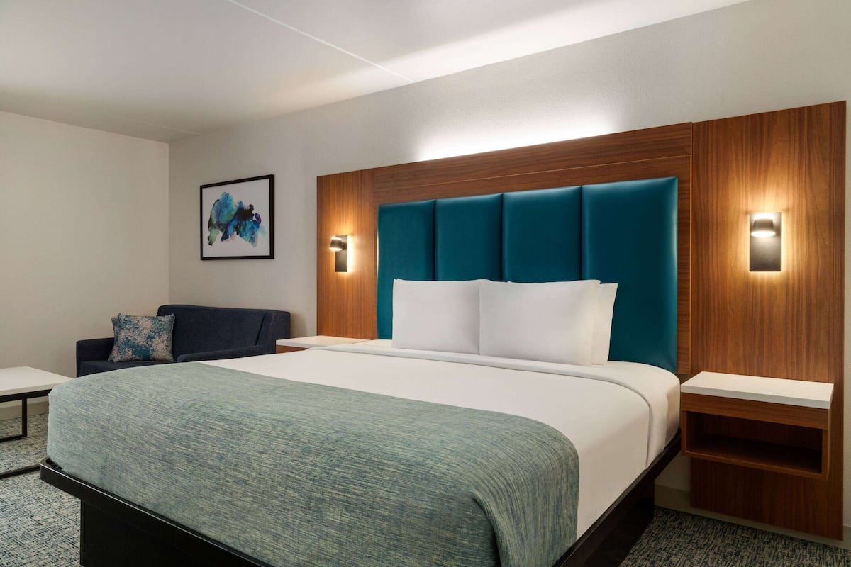 Een moderne hotelkamer met een groot bed, een houten hoofdeinde en twee nachtkastjes.