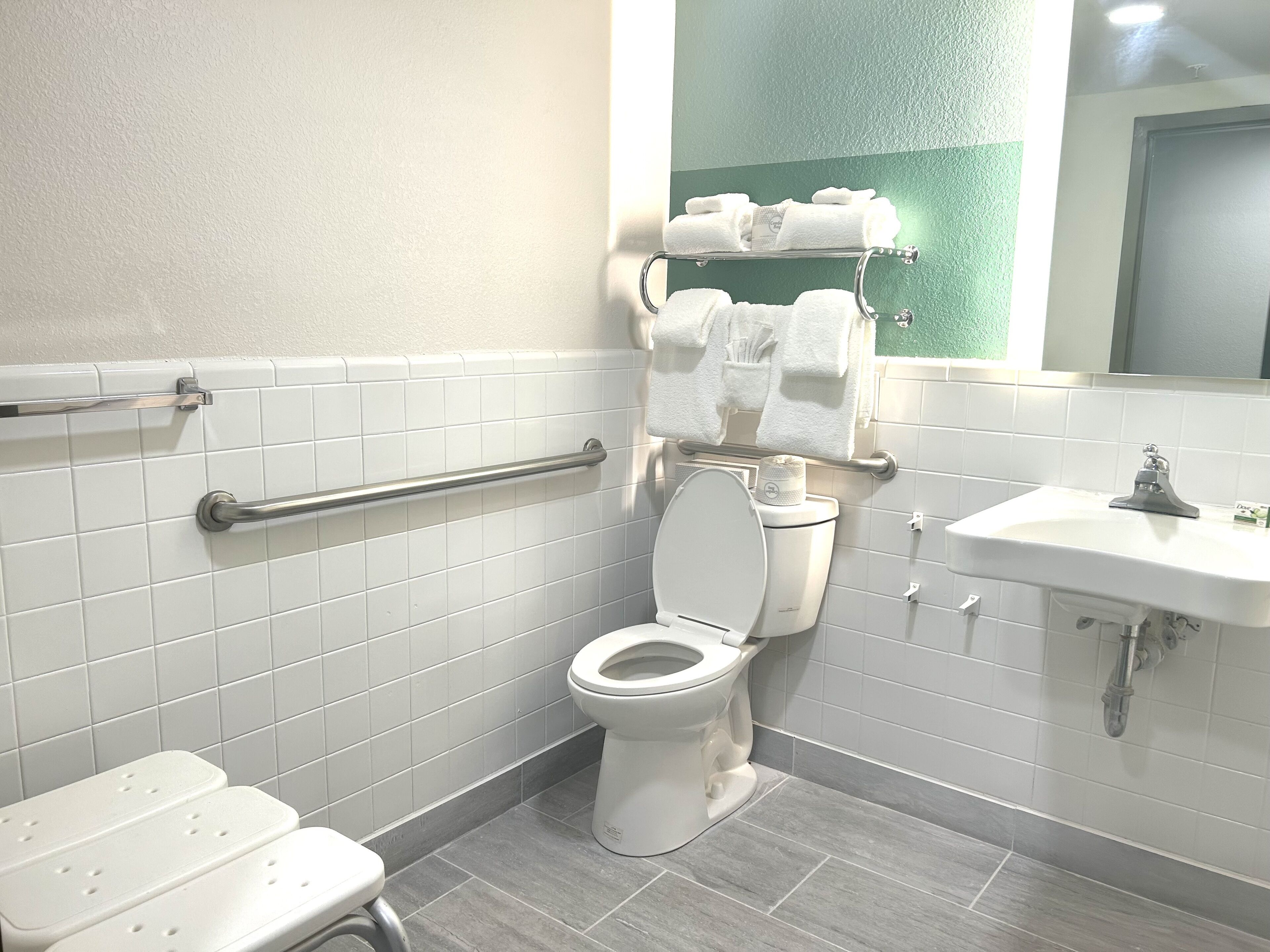 Et moderne badeværelse med toilet, gelænder, vask og håndklædestang.