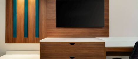 Un escritorio moderno con televisor de pantalla plana, paneles de madera y cajones integrados.
