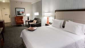 Ein Hotelzimmer mit einem großen Bett, einem Schreibtisch, einem Stuhl und zwei Nachttischlampen.