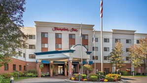 Ein Hampton Inn Hotel mit Backsteinfassade, überdachter Eingangspartei und einem angelegten Vorgarten.