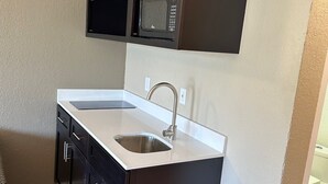 A compact kitchen with a double sink, dark cabinetry, and a microwave above the countertop. - Signature Inn Danville (Danville)