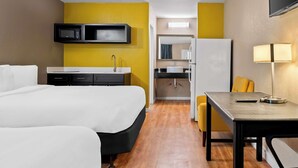 A hotel room with a bed, a desk, a microwave, a refrigerator, a sink, and a mirror. - Signature Inn Danville (Danville)
