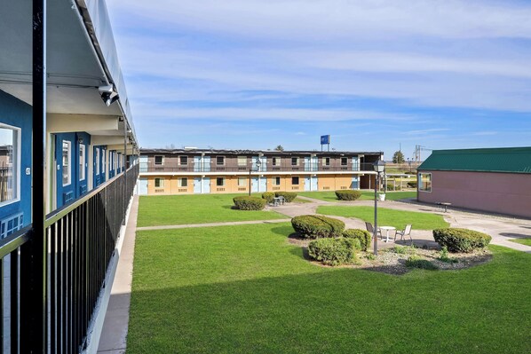 A hotel with a row of rooms, a green lawn, and a small patio area. - Signature Inn Danville (Danville)