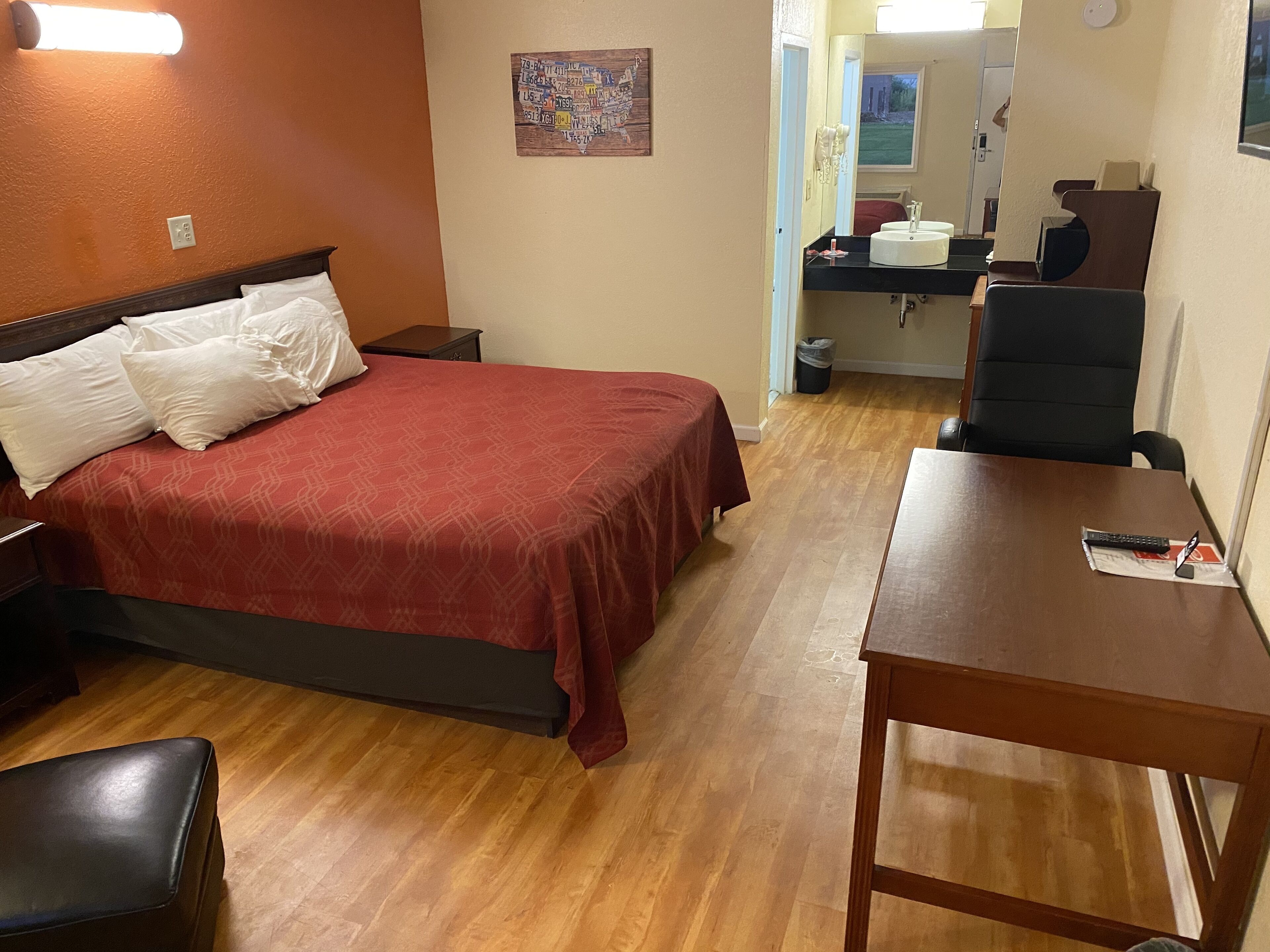 Une chambre d’hôtel comprenant un lit, un bureau, une chaise, un miroir et une petite salle de bain.