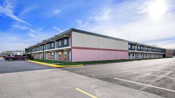 A multi-story motel with a row of rooms on the ground floor and a parking lot in front.