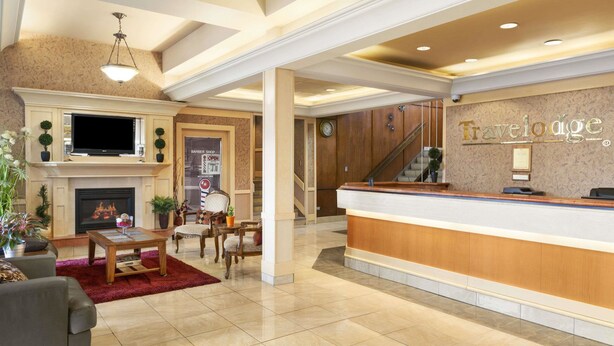 Een hotel lobby met een open haard, zithoek, receptiebalie en een trap.