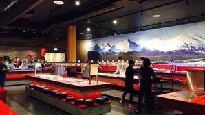 Een restaurant met een bergachtige muurschildering, een toonbank met etenswaren en een zitgedeelte met krukken.