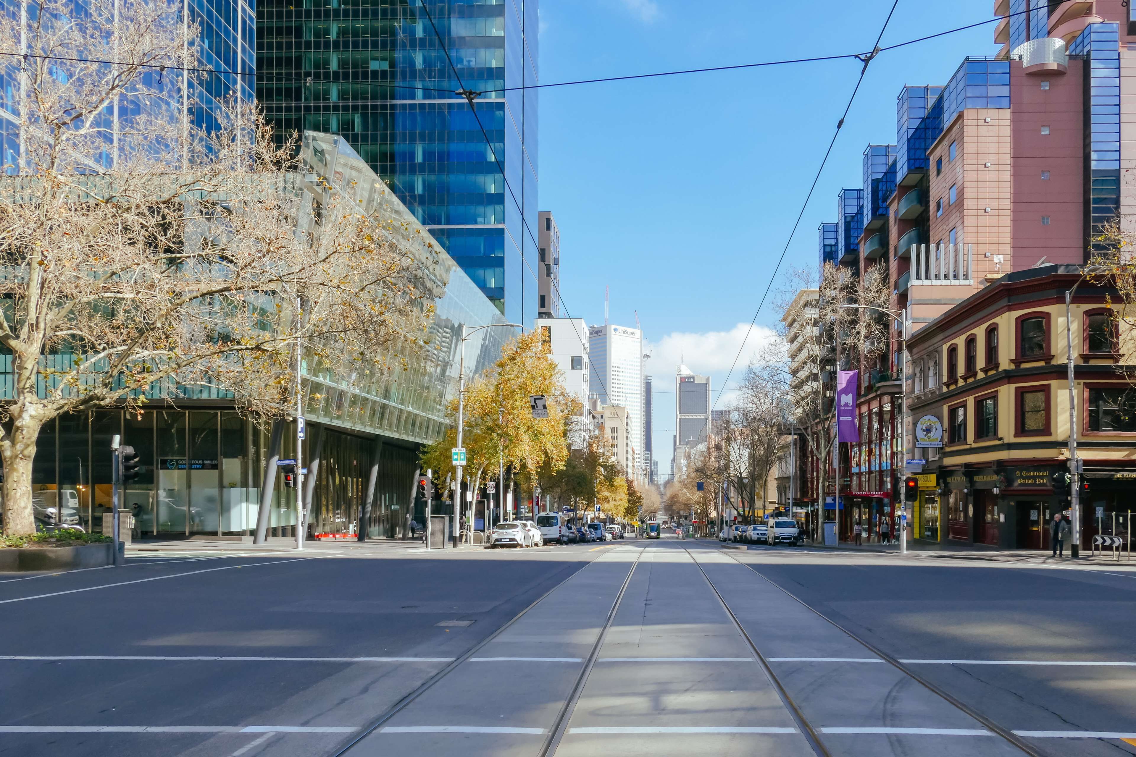 A city street with tram tracks, modern buildings, and a mix of commercial and residential structures.