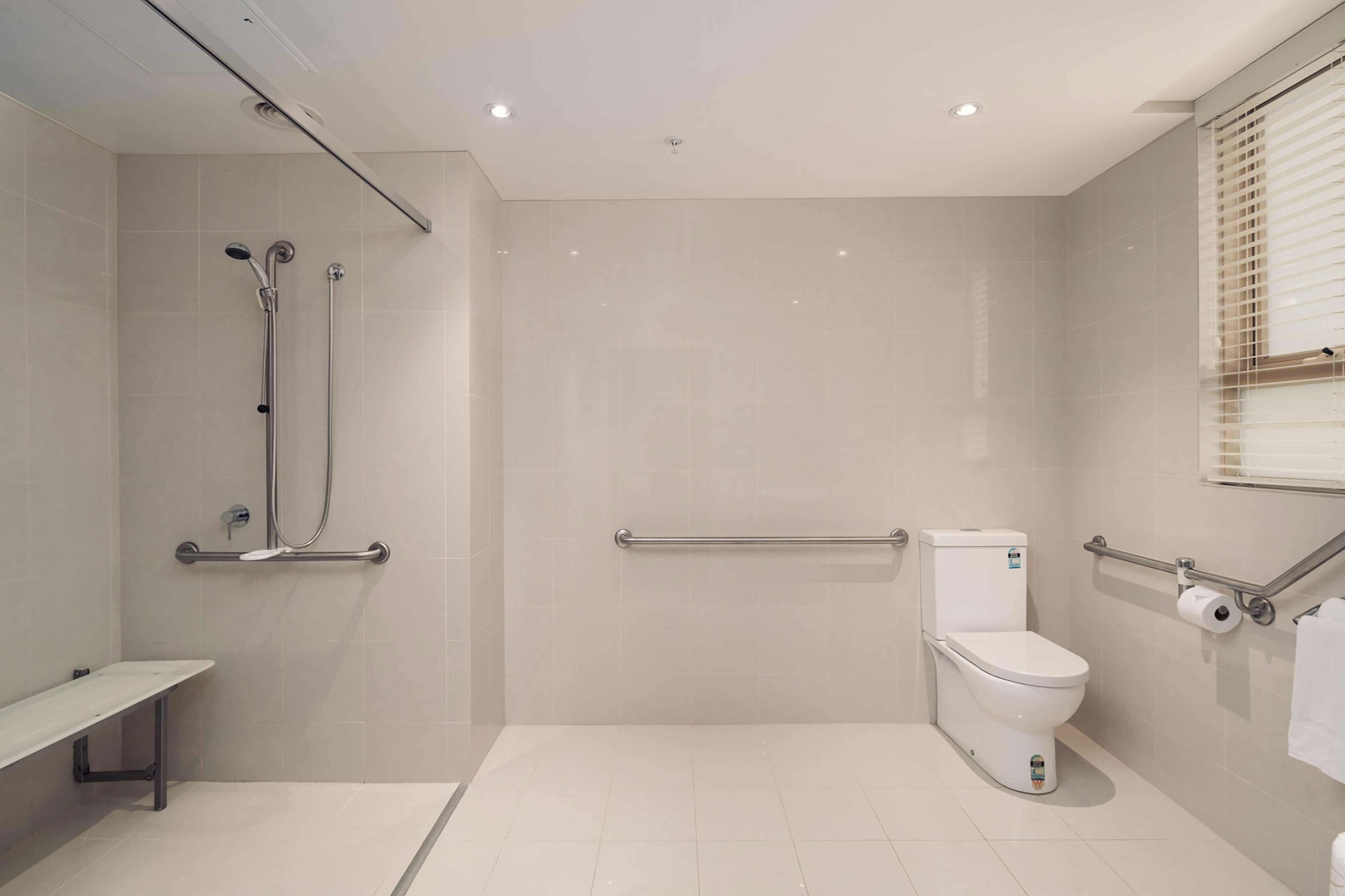 Ein modernes Badezimmer mit bodengleicher Dusche, Toilette und Sitzbank.