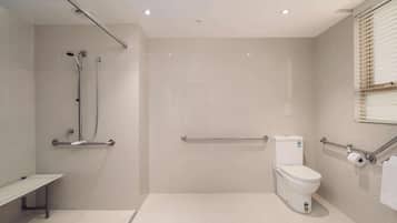 A modern bathroom with a walk-in shower, a toilet, and a bench.