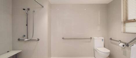 Ein modernes Badezimmer mit bodengleicher Dusche, Toilette und Sitzbank.