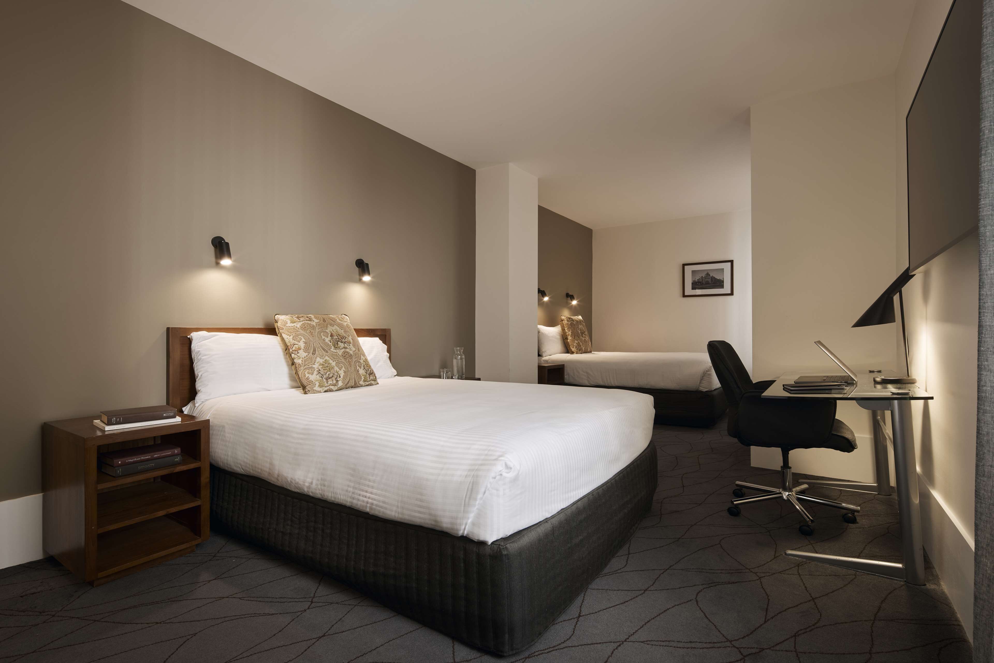 Una habitación de hotel moderna con una cama grande, un escritorio y dos mesitas de noche.