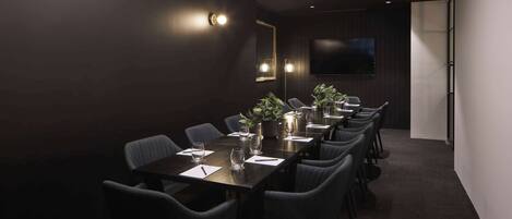 A conference room with a long table, chairs, and a plant centerpiece.