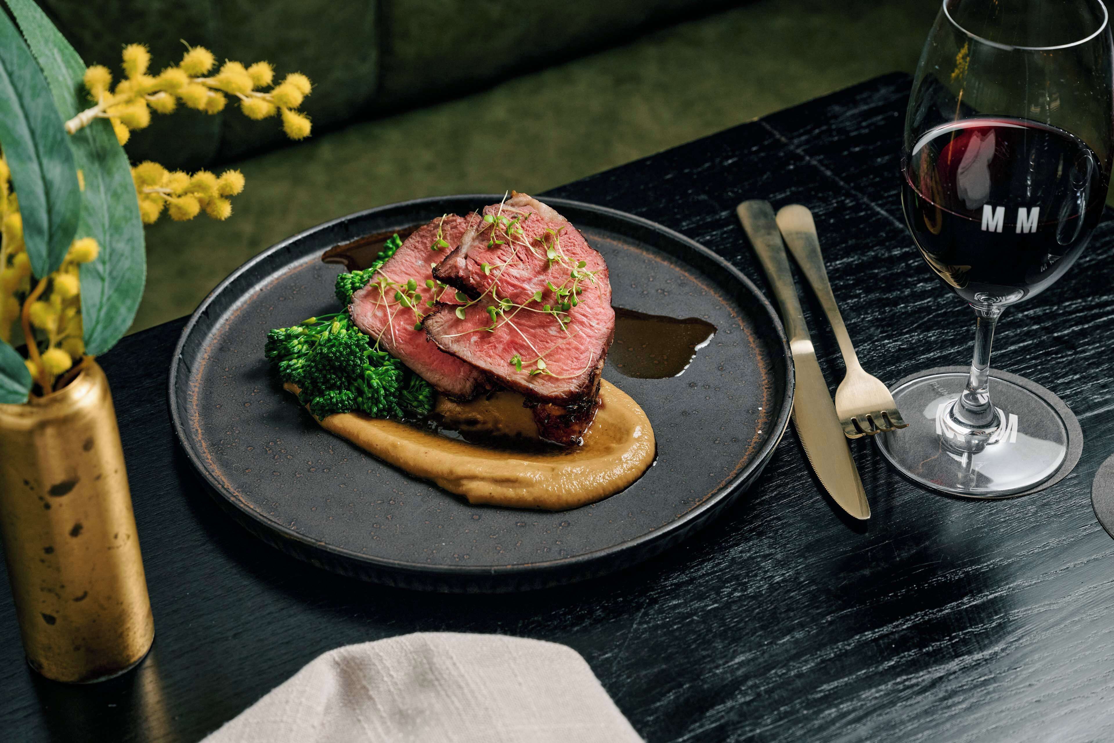 A plate of food with a glass of red wine on a table.