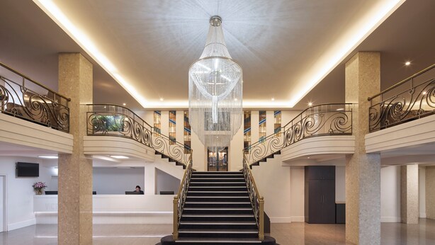 A grand lobby with a central staircase, a large chandelier, and a reception desk. - The Victoria Hotel Melbourne (Melbourne)