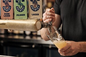 Una persona sirviendo cerveza de un grifo en un vaso.