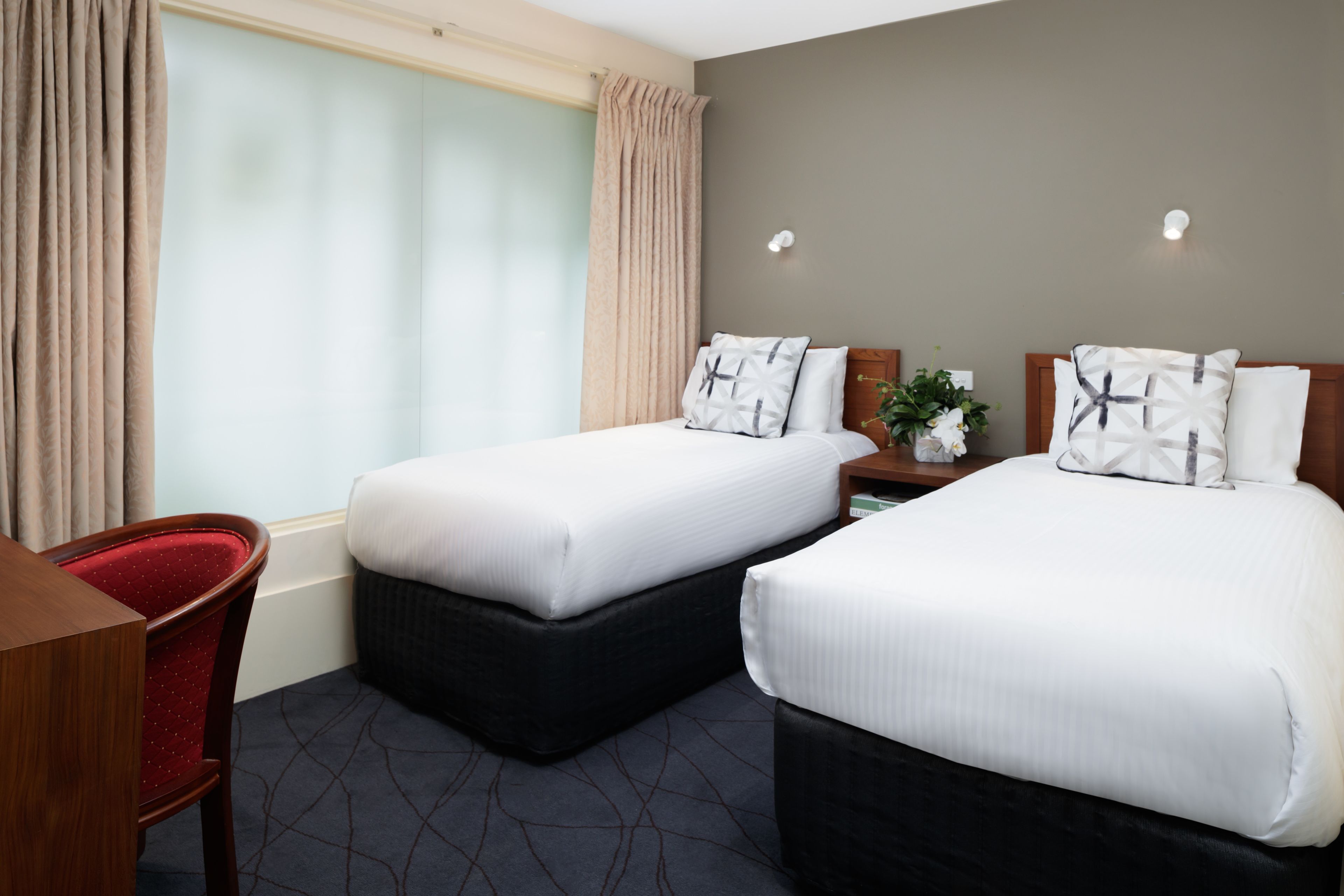 A hotel room with two beds, a desk, and a chair.