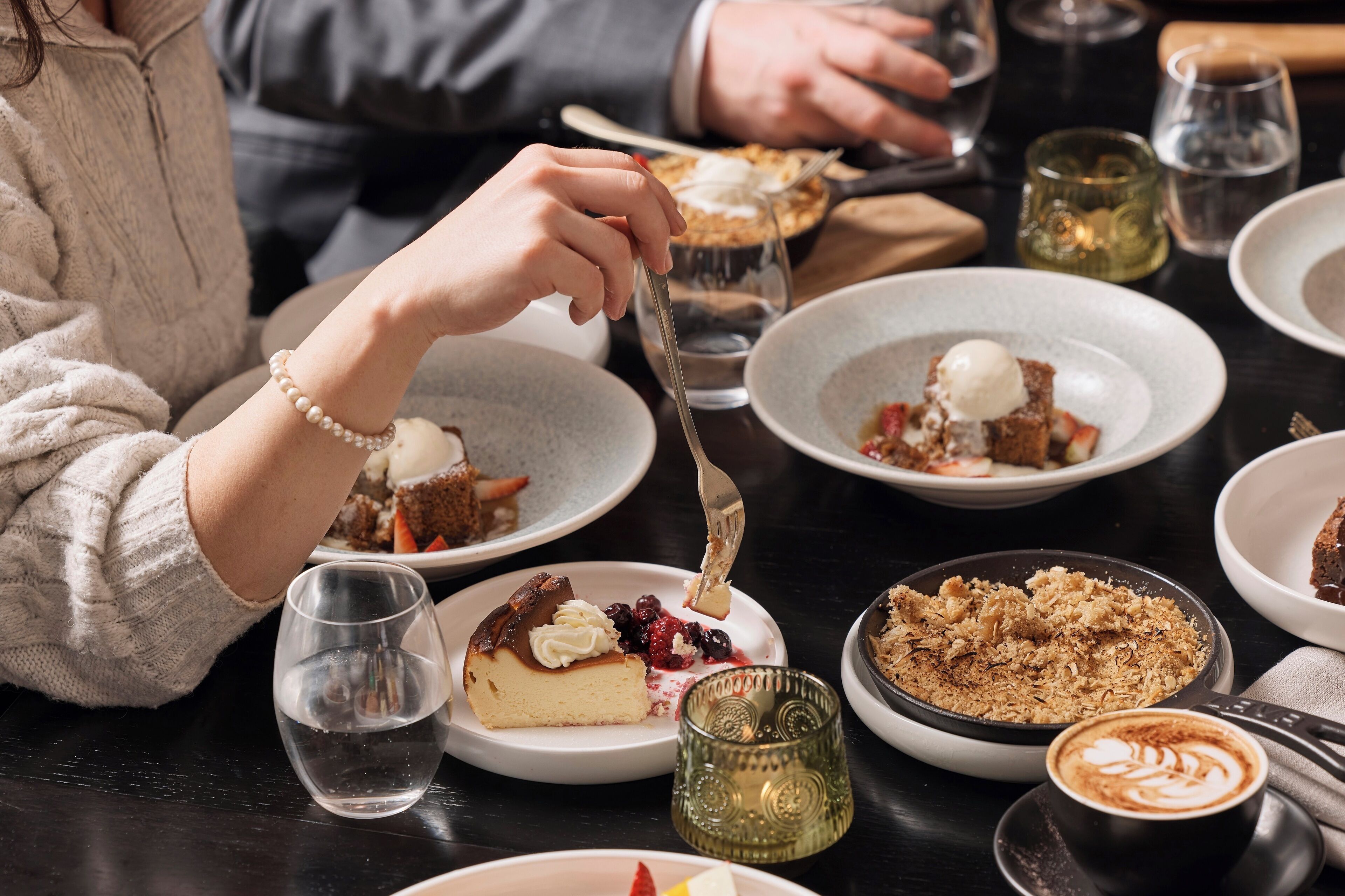 A dining table with various desserts and beverages.