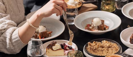 A dining table with various desserts and beverages.