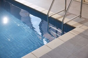 A swimming pool with tiled edges and metal handrails.